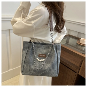 Dettaglio della borsa tote in denim grigio con catena di perle e etichetta logo in pelle