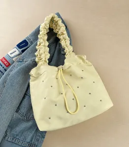 Dettaglio borsa tote beige a pieghe con coulisse e piccoli rivetti argentati