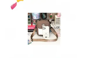 Detailed view of brown canvas crossbody bag with bear emblem and smartphone for size scale