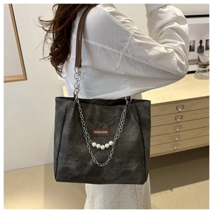 Dettaglio della borsa tote grigia con manici in pelle, catena e ciondolo di perle eleganti