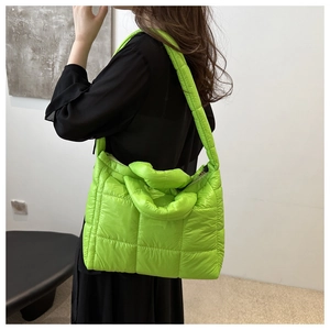 Detailed view of the vibrant green quilted nylon tote bag worn by a model on her shoulder