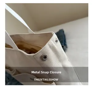 Close-up of premium metal snap button on white canvas tote bag with clear fabric texture
