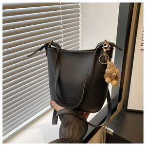 Détail du sac seau noir avec texture litchi et pendentif porte-clés ours brun mignon