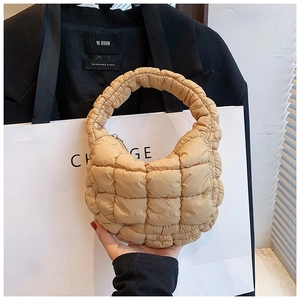 Detail of beige quilted cloud bag showing soft padded texture and top handle design