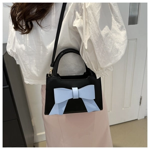 Detail of vintage black handbag with light blue bow and detachable thin strap