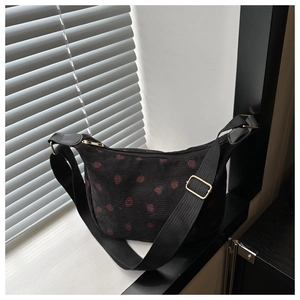 Détail du sac à main en velours côtelé noir avec motif fraise et boucle en métal