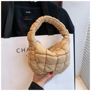 Detail of soft quilted texture and metal zipper on beige half-moon hobo bag