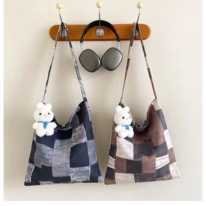 Close-up of patchwork canvas tote bags with plush rabbit charm and wide shoulder strap