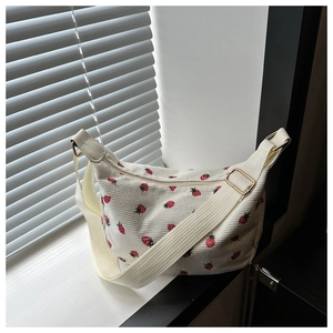 Détail du sac croissant en velours côtelé blanc avec motifs fraises et boucle dorée