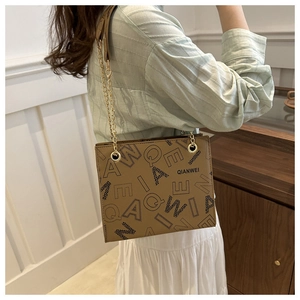 Close-up of brown leather bag featuring stylish letter print and golden chain strap