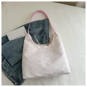 Detail shot of the white woven bubble hobo bag with a pink shoulder strap in casual setting