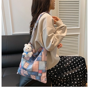 Detail of plaid canvas tote bag with plush bunny pendant shown on a female model