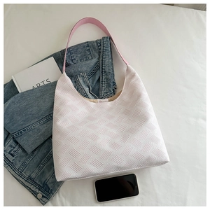 Detail of white tote bag with geometric woven texture and bright pink shoulder strap