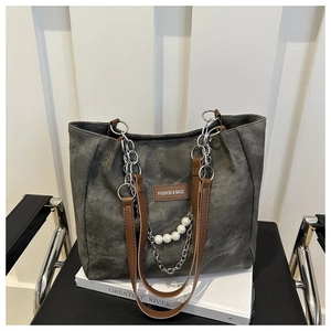 Dettaglio della borsa tote in tela grigia con manici in pelle marrone e catena con perle