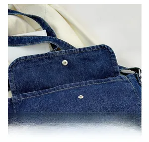 Detail view of navy blue denim crossbody bag featuring metal magnetic buckle closure