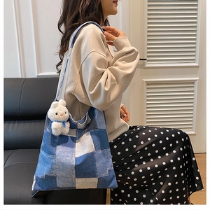 Detail of patchwork denim tote bag with white bunny charm worn by a model in a cozy room