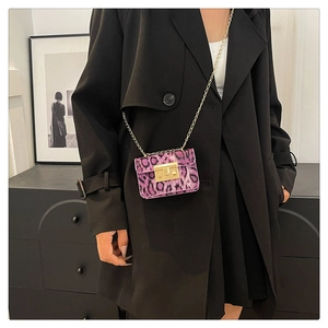 Dettaglio mini borsa leopardata viola con tracolla a catena dorata indossata su cappotto
