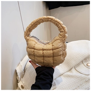 Detailed shot of khaki quilted puffer bag with soft texture and curved handle grip