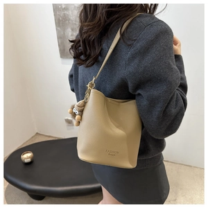 Détail du sac seau beige avec texture grainée et pendentif en peluche doux