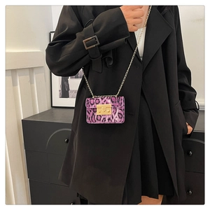 Dettaglio borsa leopardata viola con catena e chiusura dorata su cappotto nero