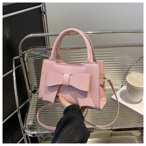 Detail of pink handbag with oversized bow decoration and elegant curved handle