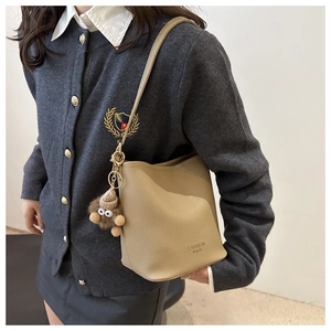 Détail du sac seau beige à grain de litchi avec un pendentif peluche petit monstre