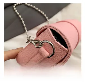 Detail of silver D-ring hook and bead chain on pink lychee grain leather saddle bag