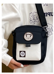 Detail of black and white canvas crossbody bag featuring a bear logo and adjustable strap