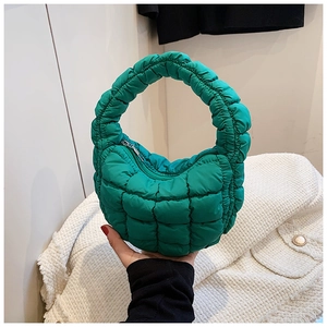 Detail of green quilted puffer handbag with padded texture and silver zipper closure