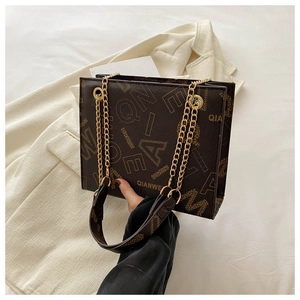 Detail of vintage brown tote bag with letter prints and metallic gold chain strap
