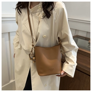 Détail du sac seau marron caramel en cuir grainé avec un adorable pendentif ours en peluche