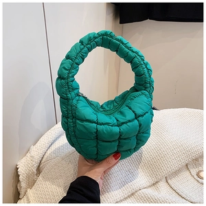 Detail view of the green quilted puffy handbag with square stitching and zip closure