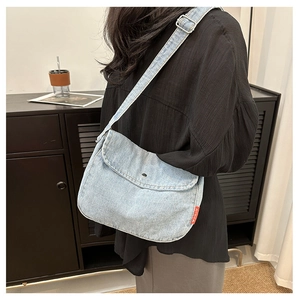 Detail view of the light blue denim crossbody bag with adjustable strap and metal buckle