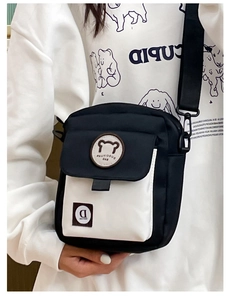 Detail of the cute bear logo and white pocket on the black canvas crossbody bag