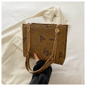 Detail of a brown leather shoulder bag with bold letter prints and gold chain strap