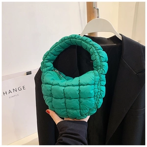 Detail of green quilted bubble bag with metallic zipper and soft down-filled texture