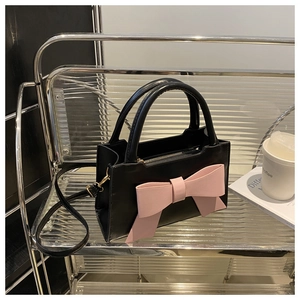 Close-up of black PU leather bag featuring a large pink bow and golden metal zipper details