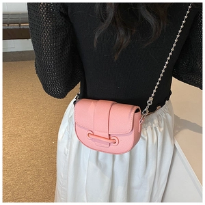 Detail of pink pebbled leather saddle bag featuring a spherical silver chain strap and flap