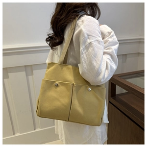 Detail of mustard yellow canvas tote bag featuring dual front pockets with silver snaps