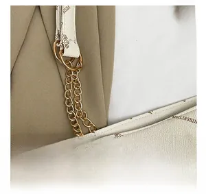 Detailaufnahme der goldenen Kette und des quadratischen Schlosses an weißer Tasche