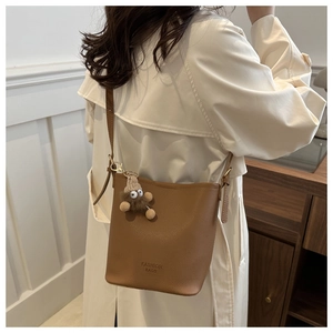 Détail du sac seau marron avec motif litchi, imprimé mode et pendentif en peluche