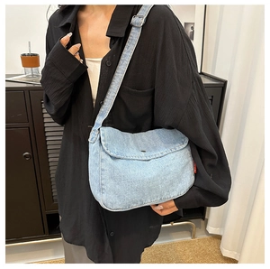 Detail view of light blue denim crossbody bag with adjustable wide strap and silver buckle
