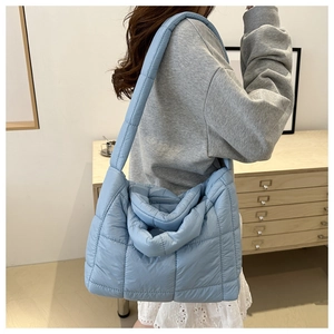 Detail view of light blue quilted puffer tote bag with padded handles and large capacity