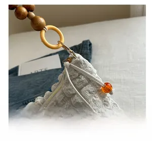 Detail of white bubble pleated bag featuring smooth zipper and amber bead charm decoration