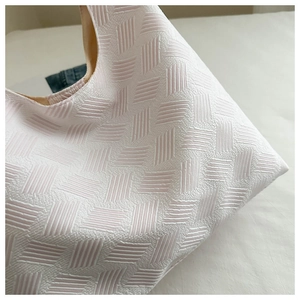Close-up detail of light pink textured bubble tote bag with embossed woven pattern