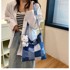 Detail of blue patchwork denim tote bag with white bunny plush charm and casual strap