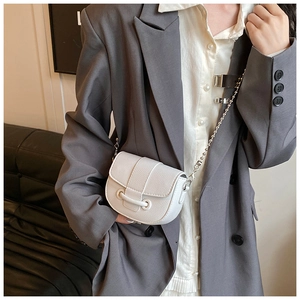 Detail of white lychee texture saddle bag with elegant silver bead chain strap and flap