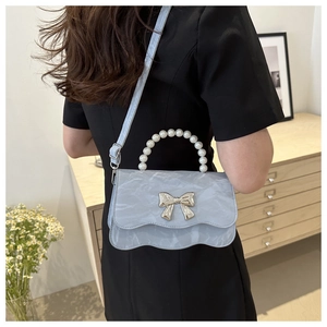 Detail of light blue marble pattern handbag with pearl handle and silver bow clasp