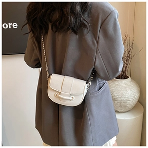 White leather saddle bag with chain strap shown on model in a modern office outfit