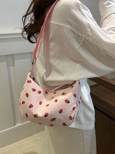 Sac hobo en velours côtelé rose avec broderie fraise porté par un mannequin